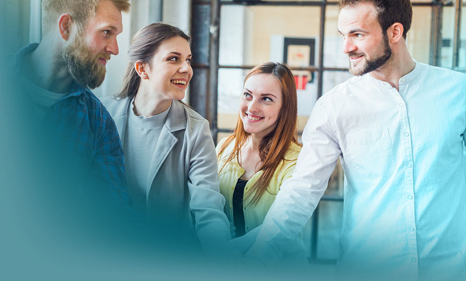 4 Phasen der Teamentwicklung: Zwei Frauen und zwei Männer in hellem Business-Outfit vereinen ihre Hände in der Mitte als Symbol für Teamspirit und Zusammenarbeit.