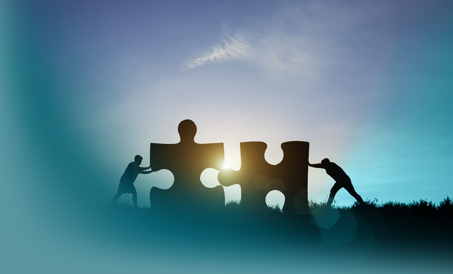Shared Leadership: Harmonisches Zusammenspiel zweier Personen beim Verbinden riesiger Puzzleteile im Sonnenlicht – Sinnbild moderner Führungskonzepte.