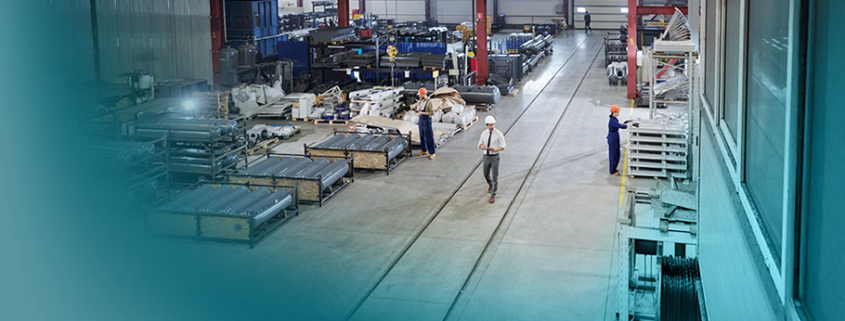 Strategie in KMU: Großräumige Industriehalle mit Fertigungsanlagen und Mitarbeitern. Symbolisiert die Produktionskraft und Vielfalt mittelständischer Unternehmen.