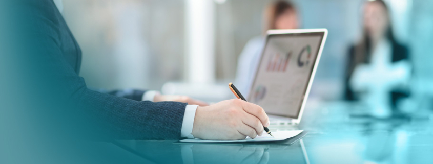 Einkaufsoptimierung: Professioneller Einkäufer bereitet sich mit Laptop und Stift auf ein wichtiges Geschäftsgespräch im hellen Konferenzraum vor.