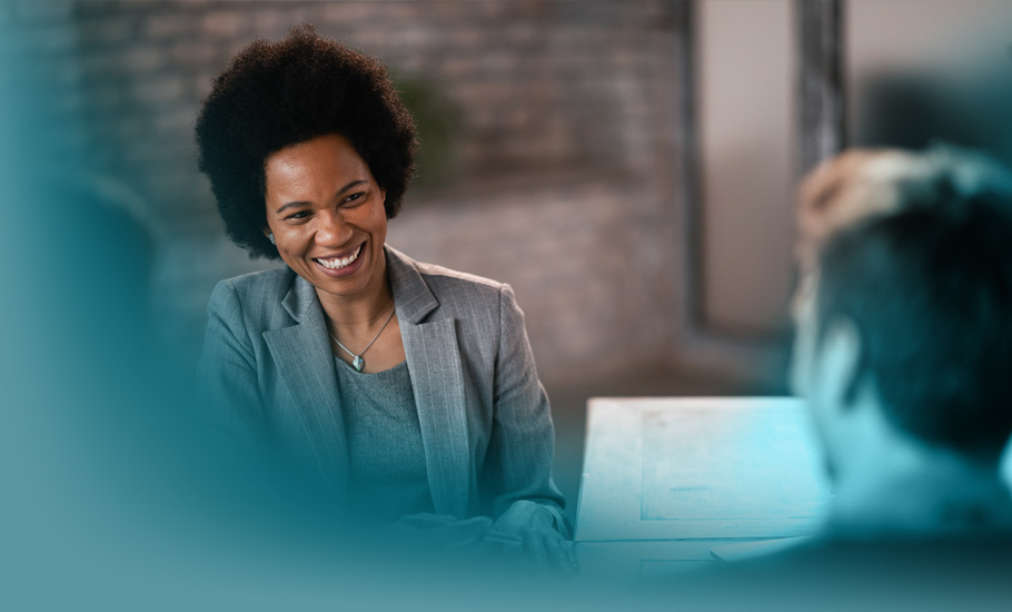 CRM im Vertrieb: Eine professionelle Beraterin im grauen Anzug bespricht in entspannter Atmosphäre wichtige Dokumente mit zwei Gesprächspartnern.