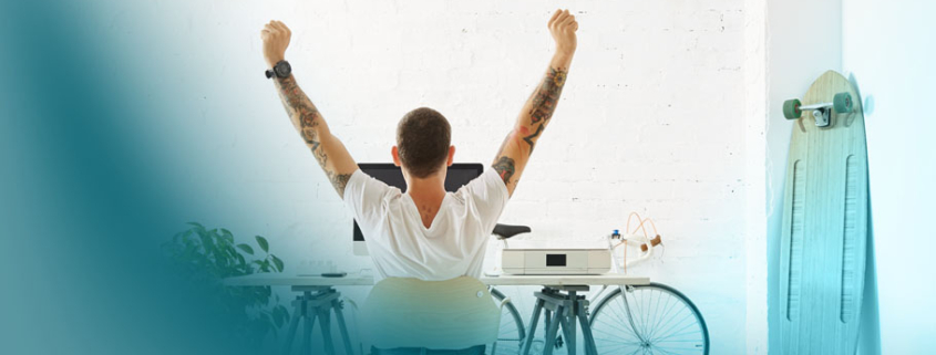 People & New Work: Motivierter Mitarbeiter genießt seinen flexiblen Arbeitsplatz mit persönlicher Note. Fahrrad und Longboard symbolisieren die neue Freiheit der Arbeitswelt.