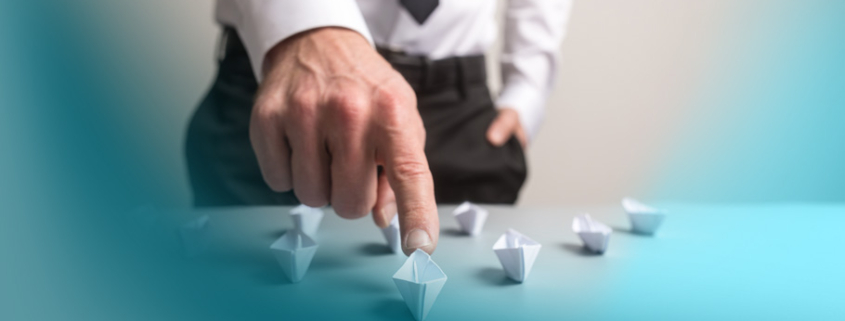 Customer Centricity: Ein Geschäftsmann in weißem Hemd und Krawatte navigiert strategisch kleine Papierboote auf einem Tisch – Symbol für die gezielte Führung von Kundenerlebnissen.