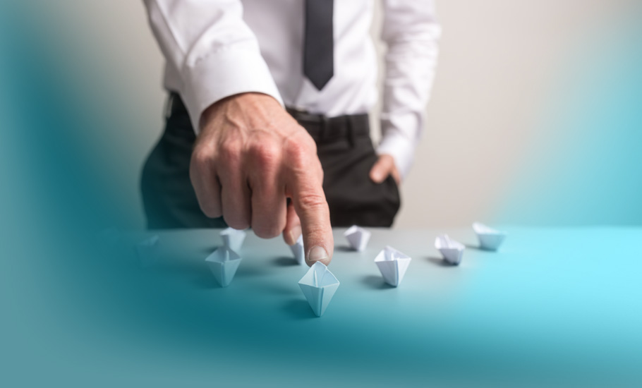 Customer Centricity: Ein Geschäftsmann in weißem Hemd und Krawatte navigiert strategisch kleine Papierboote auf einem Tisch – Symbol für die gezielte Führung von Kundenerlebnissen.