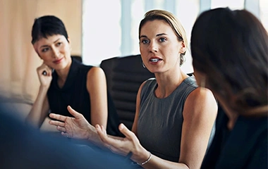 Professionelle Businessfrau kommuniziert aktiv in Teambesprechung, moderne Büroatmosphäre. Erstmals Führungskraft