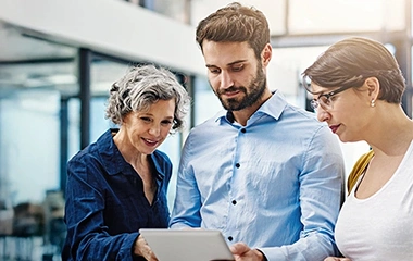 Fokussierte Teamarbeit am Arbeitsplatz, drei Kollegen schauen konzentriert auf ein Tablet. Zeitmanagement und Selbstmanagement