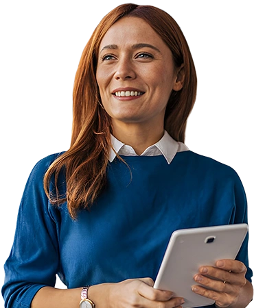 Lächelnde Frau mit roten Haaren im blauen Pullover und weißem Kragen hält Tablet vor weißem Hintergrund. Berufliche Weiterbildung