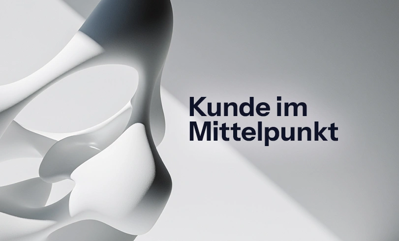 Abstrakte 3D-Skulptur auf hellem Hintergrund mit dem schwarzen Schriftzug „Kunde im Mittelpunkt". Customer Centricity