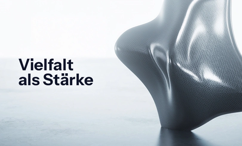 Abstrakte 3D-Skulptur auf hellem Hintergrund mit dem schwarzen Schriftzug „Vielfalt als Stärke". Diversität